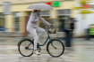 Ilustrační foto - Žena jede na kole s deštníkem v ruce. Ilustrační foto. 