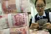 Zaměstnankyně banky ve východočínském městě Chaj-an počítá americké dolary, vpředu je stoh čínských jüanů.