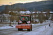 Traktor s radlicí 9. února 2021 projíždí po štěrkem posypané silnici u Záhvozdí na Prachaticku.