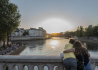 Zamilovaný pár sleduje v Paříži západ slunce a jeho odraz na hladině Seiny 14. června 2021.