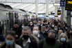 Lidé s respirátory na vlakovém nádraží Waterloo v Londýně, 14. prosince 2021.