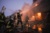 Ukrajinští hasiči zasahují u požáru budovy skladiště hořící po ruském bombardování, 17. března 2022.