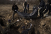 Lidé na snímku z 26. března na hřbitově v ukrajinském Charkově ukládají těla do masového hrobu. Podle pracovníků většina lidí pohřbívaných v tomto masovém hrobě zemřela z přirozených příčin a jejich těla si pak nikdo nepřišel vyzvednout.
