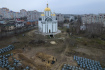 Masový hrob v ukrajinské obci Buča, v pozadí kostel svatého Ondřeje 5. dubna 2022. 