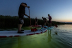 Lidé na paddleboardech s připevněnými podvodními světly plují na rekultivačním jezeře Milada při noční pozorovací jízdě života pod hladinou, 20. července 2022, Ústí nad Labem. 