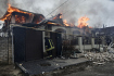 Hasič stojí u domu v ukrajinském Chersonu, který hoří po ruském ostřelování 6. ledna 2023.