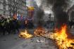 Demonstranti v Paříži míjí hořící palety během protestního pochodu proti důchodové reformě, 11. března 2023.