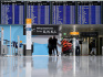Cestující stojí před tabulí s odlety na letišti v Mnichově, 26. března 2023.