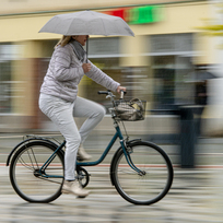 Ilustrační foto - Žena jede na kole s deštníkem v ruce. Ilustrační foto. 