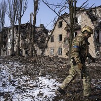 Ukrajinský policista u trosek domů v Avdijivce zničených ruskými útoky. 7. března 2023.