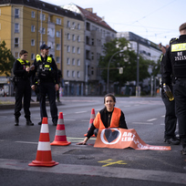 Policisté u klimatického aktivisty ze skupiny Letzte Generation (Poslední generace), který zablokoval silnici v Berlíně. 19. května 2023.