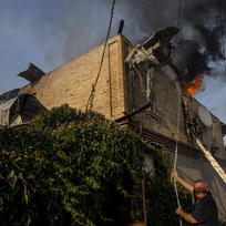 Muž se snaží hasit požár domu v Chersonu způsobený ruským ostřelováním. 9. června 2023. 