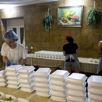 Pracovnice organizace Myrne nebo (Klidné nebe) připravují porce v humanitární kuchyni, která vaří jídlo pro lidi postižené válkou, 24. června 2023, Cherson, Ukrajina.