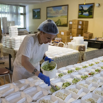 Pracovnice organizace Myrne nebo (Klidné nebe) připravuje porce v humanitární kuchyni, která vaří jídlo pro lidi postižené válkou, 24. června 2023, Cherson, Ukrajina.