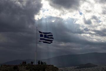 Sluneční paprsky pronikají skrze mraky na aténský Acropolis.