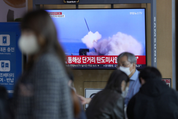 Lidé na vlakovém nádraží v jihokorejském Soulu sledují televizní reportáž o raketovém testu, který 1. října 2022 provedla KLDR.